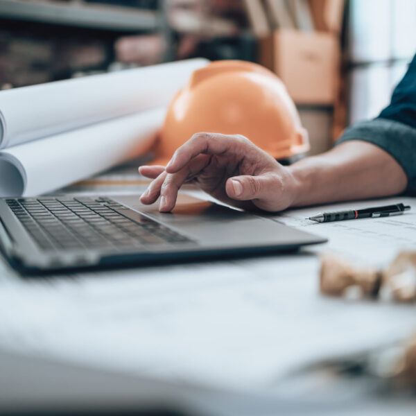 Engineering working with drawings inspection on laptop  in the office and Calculator, triangle ruler, safety glasses, compass, vernier caliper on Blueprint. Engineer, Architect, Industry and factory concept.